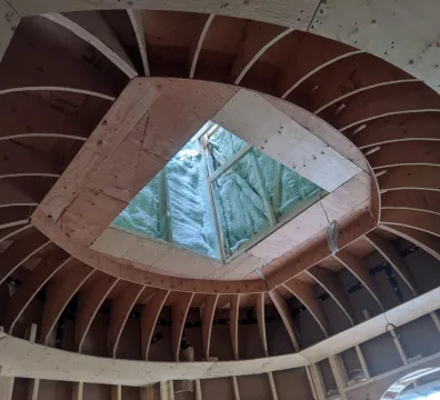 Framed curved ceiling with a central diamond-shaped skylight under construction