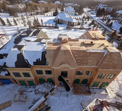 Framing of large custom estate home under snow during winter construction in the GTA